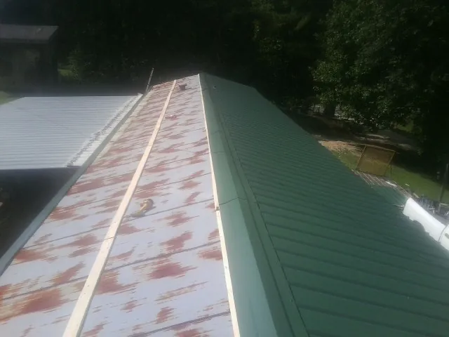 Old rusted panels beside newly installed green metal roofing — Wind Damage Roof Repair by Roofing Brothers in Hammonton