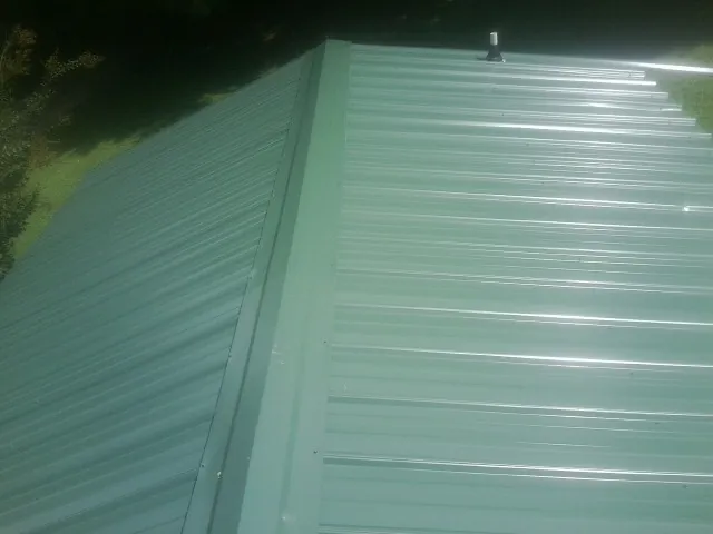 New green metal panels meeting at the ridge of a roof — Flat Roof Repair work by our crew in Hammonton
