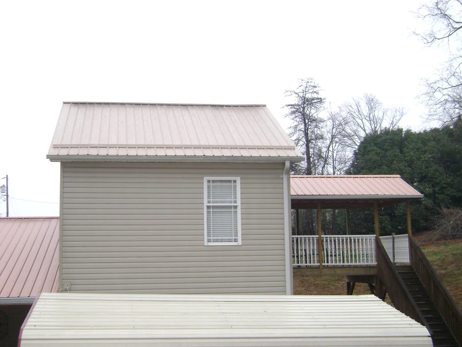 Tan metal roofs on a two story addition and attached porch, from a Roof Replacement job in Hammonton